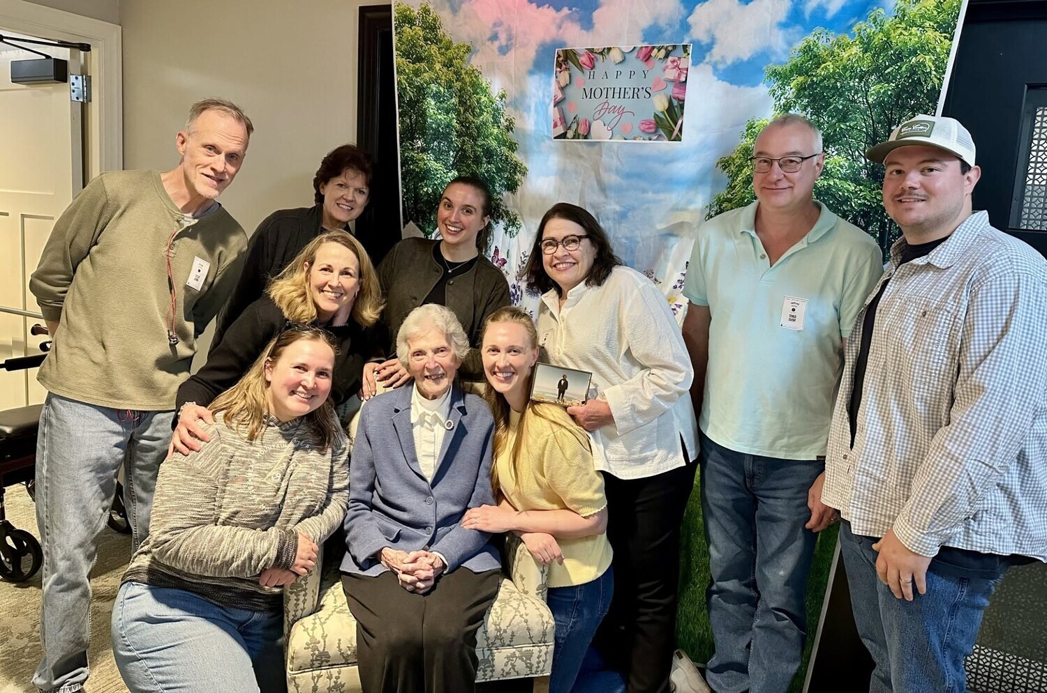 A resident poses with family members in front of a scenic outdoor backdrop during an indoor celebration, highlighting the warm sense of community found at a senior living community in Morris Plains, NJ.