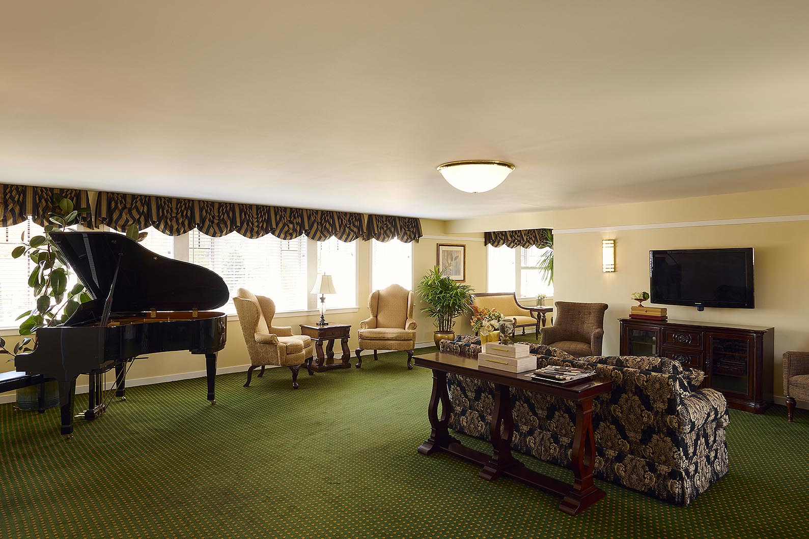 A baby grand piano, TV screen and seating in the sitting room