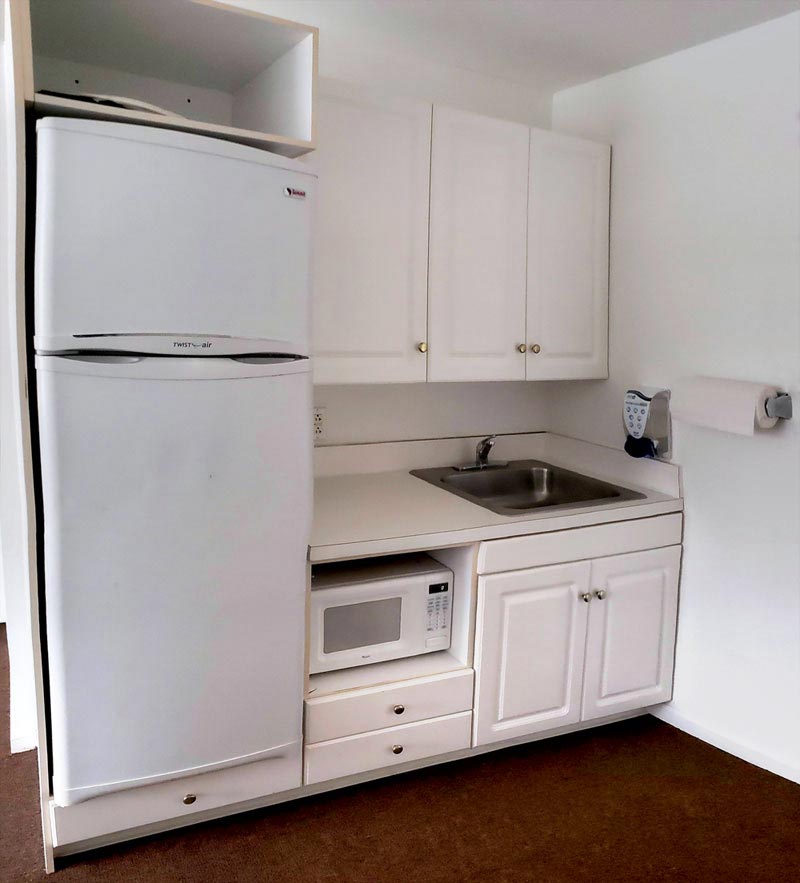 White kitchenette with refrigerator, microwave and sink